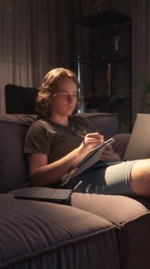 Bir öğrenci defterine yazmayı bitirir, onu kapatır ve dizüstü bilgisayarında yazmaya başlar. Bu, araştırma ve not almaktan bir deneme ya da proje yazmaya kadar olan çalışma akışını gösterir..