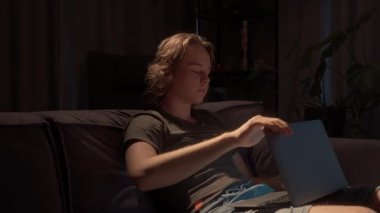 Genç bir adam işini bitirir ya da akşam için çalışır. Dizüstü bilgisayarını kapatır, defterini bırakır ve çalışma alanını kanepeye boşaltır. Bu da görevlerinin sona erdiğini gösterir..