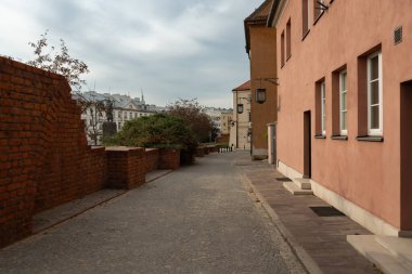 Varşova 'nın Eski Kasabası' nın tarihi tuğla duvarlarının yanında kaldırım taşlı bir sokak manzarası sunuyor. Turizm ve turizm için sakin bir yol..