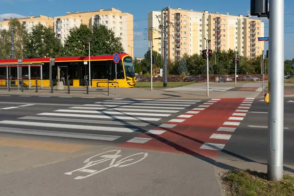 Varşova 'da tam bir kentsel ekosistem: tramvay, bisiklet yolu ve yaya geçidi, arka plandaki modern apartman sakinlerine entegre ulaşım sağlar.