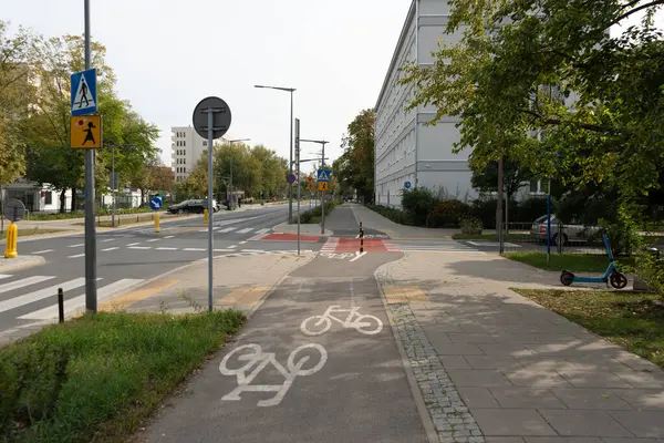 Varşova 'da organize trafik akışı olan modern bir şehir caddesi manzarası. Adanmış bir bisiklet yolu ve kaldırım çok şeritli yola paralel gidiyor..
