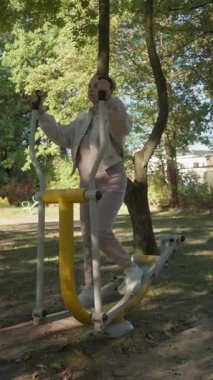 Bir kadın halka açık bir parkta egzersiz yapıyor, temiz havada egzersiz yapıyor. Doğada eğitim hem fiziksel hem de zihinsel refah için sağlıklı bir yaşam tarzı seçimidir..