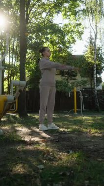 Bir kadın kol halkaları yapar, omuzlarını ısıtmak için dinamik bir esneme egzersizi. Bu hareketlilik rutini omuz eklemlerini egzersize hazırlar ve yaralanmaları önler..