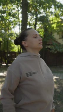 Bir kadın sırtını ısıtmak ve gerilimi azaltmak için omuz silkme egzersizi yapar. Bu hareketlilik egzersizi trapezius kaslarını hedef alır ve sertliği azaltmaya yardımcı olur..