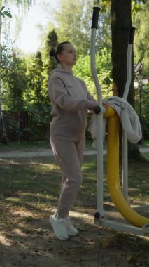 Bir kadın tek bacaklı baldır kaldırıyor, açık hava spor aletlerini denge için kullanıyor. Bu egzersiz baldır kaslarını hedefler ve güçlendirir ve ayak bileği dengesini arttırır..