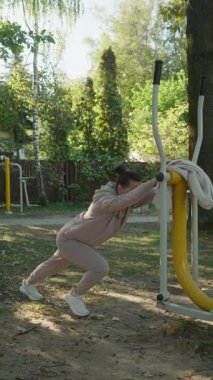 Bir kadın, açık hava spor aletlerine karşı baldır esneme hareketi yapıyor. Bu soğutma egzersizi bacak esnekliğini artırır ve kas iyileşmesi ve yaralanmayı önlemeye yardımcı olur..