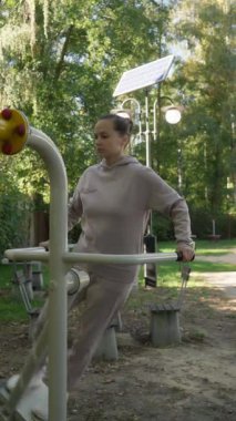 Bir kadın vücut kaslarını spor salonunda hava sallama makinesinde çalıştırıyor. Bu bükülme, yan yana hareket kuvvet çalışması için eğiklikleri ve beli hedef alır..