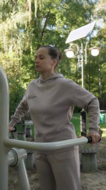 Bir kadın açık hava makinesinde egzersiz yaparken odaklanma ve konsantrasyonunu koruyor. Onun pürüzsüz, ritmik, yan yana hareketi aktif bir meditasyon ve vücut kontrolü şeklidir..