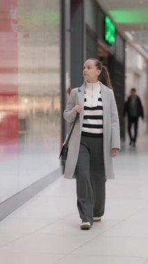 Düşünceli bir tüketici mağazaların önünden geçiyor, seçici bir şekilde vitrinlere bakıyor. Bu, hızlı modanın gerilediğini ve bilinçli tüketim çağındaki perakende satış merkezlerinin zorluğunu gösteriyor..