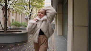 Güzel, karizmatik bir kadın sonbahar parkında yürümekten zevk alıyor. Şakacı bir şekilde poz veriyor, gülümsüyor ve kamerayla flört ediyor. Kendine güven ve yüksek özgüven kavramı..