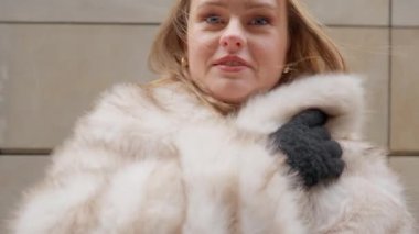 Samimi bir kürk manto giyen genç bir kadın ve eldivenler soğuktan titriyor, sonra moda el çantasını bir hayvan iziyle gösteriyor. Sıcak kış kıyafetlerini tanıtmak için mükemmel bir klip..
