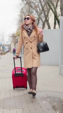Bağımsız kadın valiziyle yalnız seyahat ediyor, şehir caddesinde yürüyor. Şık bir bayan turist ya da iş adamı tatil ya da buluşma yerine varıyor..