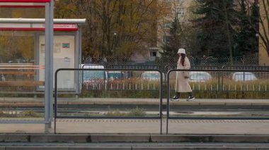Genç bir kadın tramvay peronunda volta atarak zamanını geçirir. Soğuk bir sonbahar gününde toplu taşıma araçlarının gelmesini sabırla bekleyen bir şehir banliyö çalışanı..