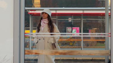 Genç bir kadın sabırla otobüs ya da tramvay bekliyor. Bir şehir sakininin işe gitmesini beklerken telefonuna baktığı samimi, hayat dolu bir an..