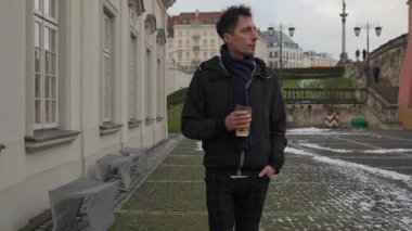 Sıcak bir kahveyle ısınan bir adam soğuk bir günde Polonya, Varşova 'da yürür. Düşünceli bir kış yürüyüşü için giyinmiş tarihi bir kaldırım taşı caddesinde günlük rutinine sessiz bir ara vermiş..