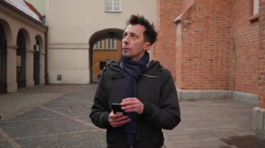 Bir adam fotoğraf çekmek ya da tarihi mimarinin video kaydını yapmak için akıllı telefon kamerasını kullanır. Bu turist ya da seyahat blogcusu Varşova 'yı keşfederken sosyal medya için dijital içerik oluşturuyor.