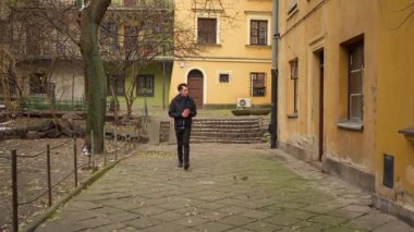 Bir adam sert bir kış gününde nemli ve serin bir şehir avlusunda yürüyor. Rüzgâr, Varşova 'nın tarihi sokaklarında tek başına dolaşırken kaldırım boyunca kuru yapraklar savuruyor..