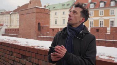 Bir turist Varşova 'nın tarihi bir simgesini keşfetmek için rehber uygulamalı bir cep telefonu kullanır. Geçmişi öğrenir ve kış yolculuğunu hatırlamak için bir fotoğraf ya da video çeker..