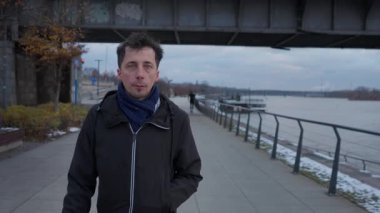 Sakin ve rahat bir ifadeye sahip bir adam şehir setinde tek başına yürür. Soğuk kış gününün yalnızlığını ve gri atmosferini kucaklayan barışçıl bir kabullenme anı bulur..