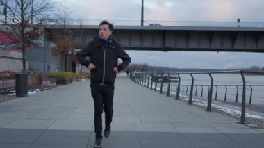 Bir adam kışın Vistula nehrinin kenarındaki geniş şehir seti boyunca tek başına yürüyüşe çıkar. Elleri ceplerinde gezer, bulutlu bir günde soğuk, kentsel manzarayı gözlemler..