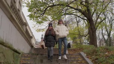 Genç bir adam ve bir kadın halka açık bir parkta taş bir merdivenden iniyorlar. Zemin sonbahar yaprakları ve ilk kar parçalarıyla kaplı. Bu da sonbaharın sonlarında veya kış başlarında atmosfer yaratıyor..