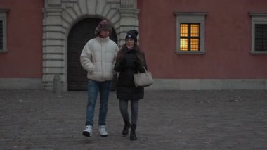 Genç bir çift soğuk bir kış akşamında tarihi bir şehir meydanında sessiz ve romantik bir gezinti yapıyor. Kalın giysiler içinde, eski mimari ile çevrili bir anı paylaşıyorlar..