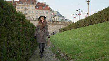 Şık bir turist Varşova 'nın Eski Kasabası manzaralı bir yolda yürüyor. Arka planda ikonik Sigismund Sütunu var. Castle Meydanı 'nın ünlü simgesidir..