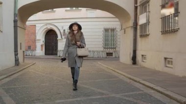 Tarz sahibi bir kadın, tarihi bir kemer altında yürüyen Varşova 'nın eski kasabasının büyüleyici dar sokaklarını keşfediyor. Bir turizm, keşif ve gizli mücevherleri keşfetme kavramı..