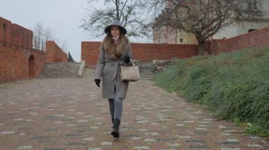 Yalnız bir kadın tarihi bir yolda yürüyor, düşünceli ve düşünceli görünüyor. Kişisel yolculuk kavramı, kendi yansıması, ve insanın kendi yolunda gitmesi..