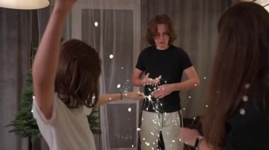A family faces a holiday challenge with visible frustration, untangling a messy knot of festive lights. This shows the difficult and stressful reality of holiday preparations.