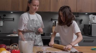 Bir çocuk hamuru yuvarlarken bir hata yapar merdaneye yapışır ve bir kıvrım yaratır. Anne müdahale eder, merdaneyi alır ve sabırla hatayı düzeltir ve hamuru düzeltir..