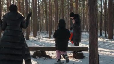 Mutlu bir aile kış gününün tadını çıkarır, ormanda kartopu savaşı yapar. Ebeveynler ve çocuklar güler, kar atar ve karlı bir parkta eğlenceli bir hafta sonu geçirirler.