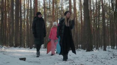 İki çocuklu mutlu bir aile, karlı bir ormanda hafta sonu yürüyüşünün tadını çıkarıyor. Ebeveynler ve çocukları sağlıklı ve aktif bir yaşam sürüyorlar. Soğuk ve güneşli bir günde boş zamanlarını birlikte geçiriyorlar..