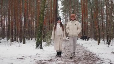 Bir anne ve genç oğlu, karlı bir çam ormanında sakin bir yürüyüş yapıyorlar. Dışarıda huzurlu bir aile hafta sonu, doğanın tadını çıkarmak ve birlikte güzel vakit geçirmek. Pozitif aile değerleri.