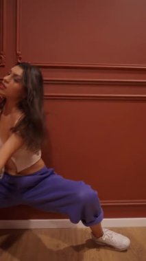 Stüdyoda genç bir kadın vücudunu dans çalışmasına hazırlamak için ısınma egzersizi yapıyor. Bu esneklik ve soğutma egzersizleri kas bakımı ve yaralanma önleme için gereklidir..