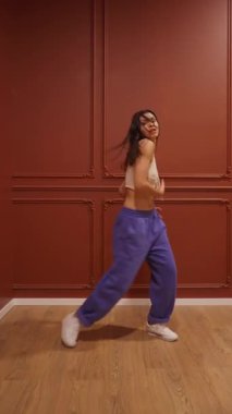 Şımarık kişilikli karizmatik bir genç kadın eğlenceli bir hip-hop dansı yapıyor. Eğlenceli, şık hareketleri ve alımlı görünüşü popüler bir sosyal medya videosu ya da müzik klibi için mükemmel..