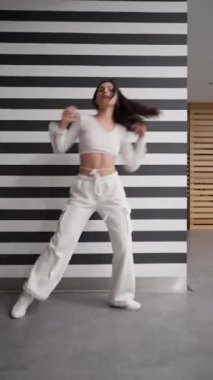 Genç bir içerik yaratıcısı sosyal medya yarışması için modaya uygun bir hip hop dansı yapıyor. Bu kadın etkili, takipçileri için ilgi çekici bir içerik oluşturan havalı ve kendinden emin hareketler sergiliyor..