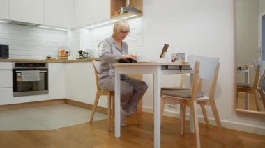 Gözlüklü son sınıf öğrencisi bir kadın masasında oturur ve sessiz bir sabahın tadını çıkarır. Sıcak kahve içer ve kitap okur. Huzurlu bir hobi ve hayat boyu öğrenme sahnesi..