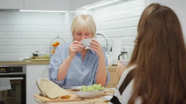 Güzel yaşlı bir kadın mutfakta kızıyla çay içerken gülümser ve konuşur. Akıl hocalığı, tecrübe aktarma ve güven dolu bir aile ilişkisi..