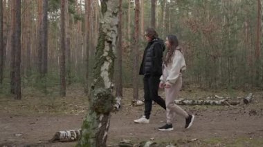 Genç bir çift ormanda rahatlatıcı bir yürüyüş sırasında keyifli bir sohbetin tadını çıkarıyor. Kadın konuşurken gülümser ve el kol hareketi yapar. Huzurlu bir günde erkek arkadaşıyla bir hikaye paylaşır..