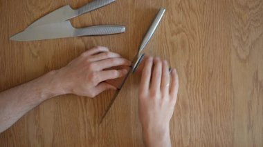 Bıçak bileyicisiyle bileyleme işlemi devam ediyor. Bir adam mükemmel bir bıçak kenarı için kaba öğütücülükten ince bilenmiş öğütücüye geçmek için aleti çevirir. Özgün sesi içerir.