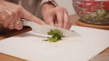Bir ev hanımı kesme tahtasının üzerinde şefin bıçağıyla taze yeşil dereotu doğruyor. Ev yapımı salataya tat ve baharat katmak için aromatik otlar hazırlıyorum. Sağlıklı bir vejetaryen bileşeni..