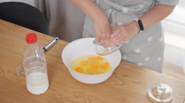 Ev hanımı omlet hamuru hazırlıyor, mutfağa tuz ve çırpılmış yumurta ekliyor. Taze malzemeler ve sütten ev yapımı kahvaltı hazırlama süreci.