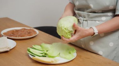 Bir aşçı taze marul yapraklarını koparır, sebze dolgusunu shawarma için hazırlar. Ev yapımı kebap ya da tavuk sarması için lavaş gibi malzemeler yapma süreci..