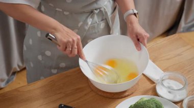 Bir kadın brokoli ile kiş yapmak için çırpılmış yumurtayı karıştırma kabında çırpar. Vejetaryen kahvaltısı hazırlama ya da evcil mutfakta lezzetli bir ev yemeği hazırlama süreci..