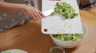 Yumurta ve krema karışımlı bir kaseye doğranmış brokoli ekliyorum. Bir kadın vejetaryen kiş ya da lezzetli turta yapmak için malzemeleri karıştırıyor. Adım adım ev yapımı bir tarif..