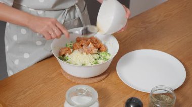 Somon ve brokoli için son dolguyu hazırlıyorum. Bir kadın balık parçaları ekler ve tüm malzemeleri bir kasede birleştirir. Adım adım sağlıklı deniz ürünleri içeren bir gurme tarifi..