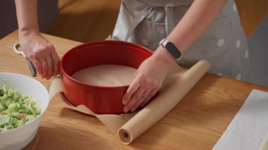 Yemek tarifi için tava hazırlıyorum. Bir kadın yapışmaz parşömen kağıdıyla yay şeklinde bir pasta kutusu çiziyor. Ev yapımı turta, pasta ya da kiş için hazırlık süreci.