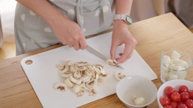 Kesme tahtasında taze şampiyon mantarları doğramak. Bir kadın lezzetli ev yapımı pizza ya da pinsa pişirmek için doğal malzemeler hazırlar. Sağlıklı vejetaryen gıda konsepti.