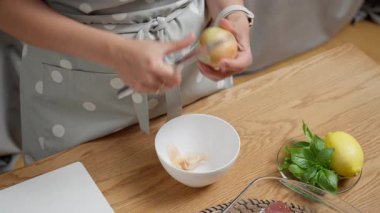 Mutfakta bir kadın bıçakla çiğ sarı soğanın derisini soyuyor. Ev yapımı yemek için taze sebze malzemeleri hazırlıyorum. Sağlıklı bir salata veya vejetaryen yemeği için yemek dilimlemek..